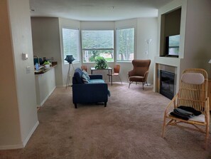 A living room with a blue sofa, a wooden chair, a small table, and a fireplace.