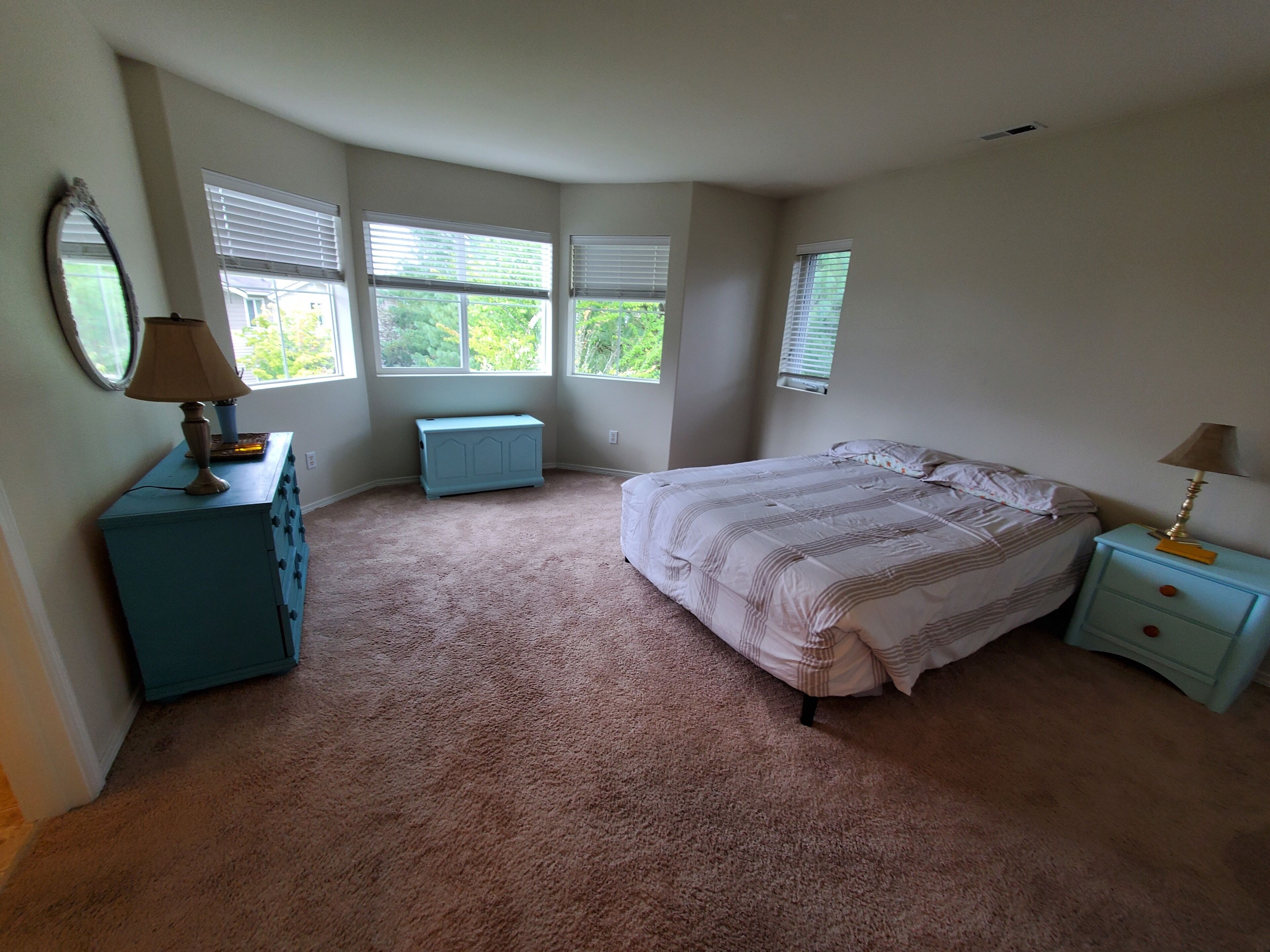 Une chambre à coucher avec un grand lit, une commode, une table de chevet et un radiateur.