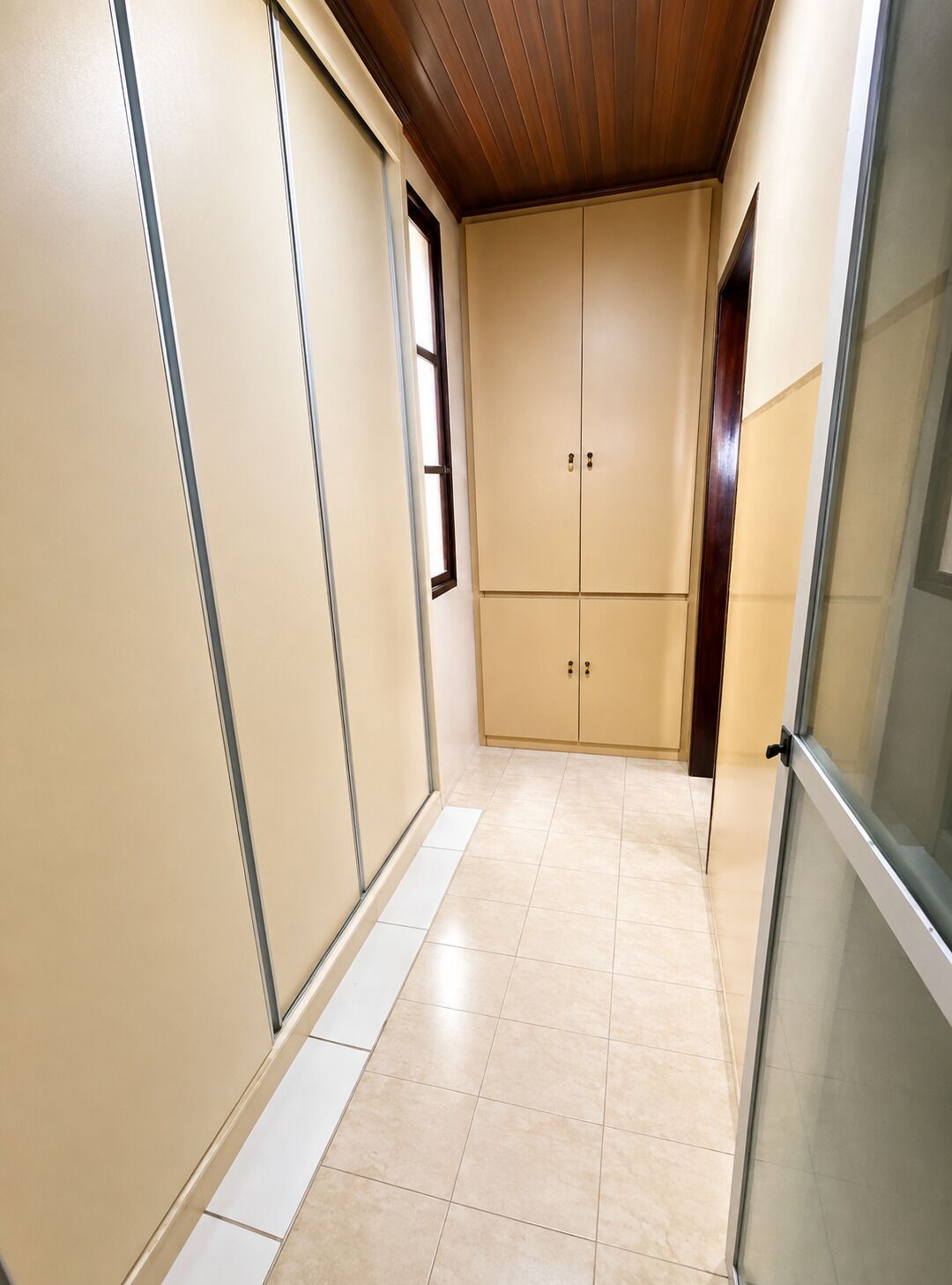 A hallway with sliding doors, a tiled floor, and a wooden ceiling.