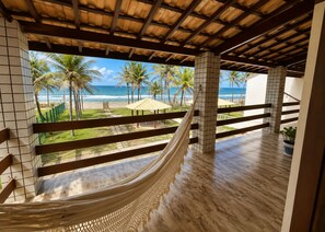 Un'amaca sotto un soffitto in legno con vista sulla spiaggia e palme.
