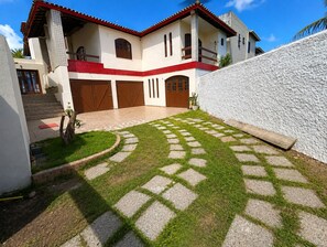 Une maison à deux étages avec une allée pavée et une petite pelouse.