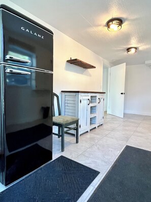 A modern kitchen with a black refrigerator, a wooden cabinet, and a chair. - Canyon Lake Chalet - Firepit, Hot tub, Boat Parking (Canyon Lake)
