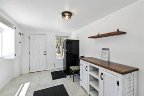 A room with a white door, a black refrigerator, a wooden shelf, and a sign on the wall. - Canyon Lake Chalet - Firepit, Hot tub, Boat Parking (Canyon Lake)