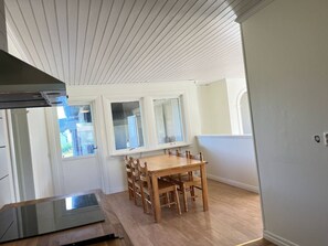 A kitchen with a wooden table and chairs, a window, and a built-in stove. - Room-room 3 in Vålberg, Karlstad (Vålberg)