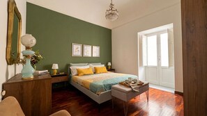 Una camera da letto con un letto, comodini, un tavolo da notte, una finestra e un lampadario.