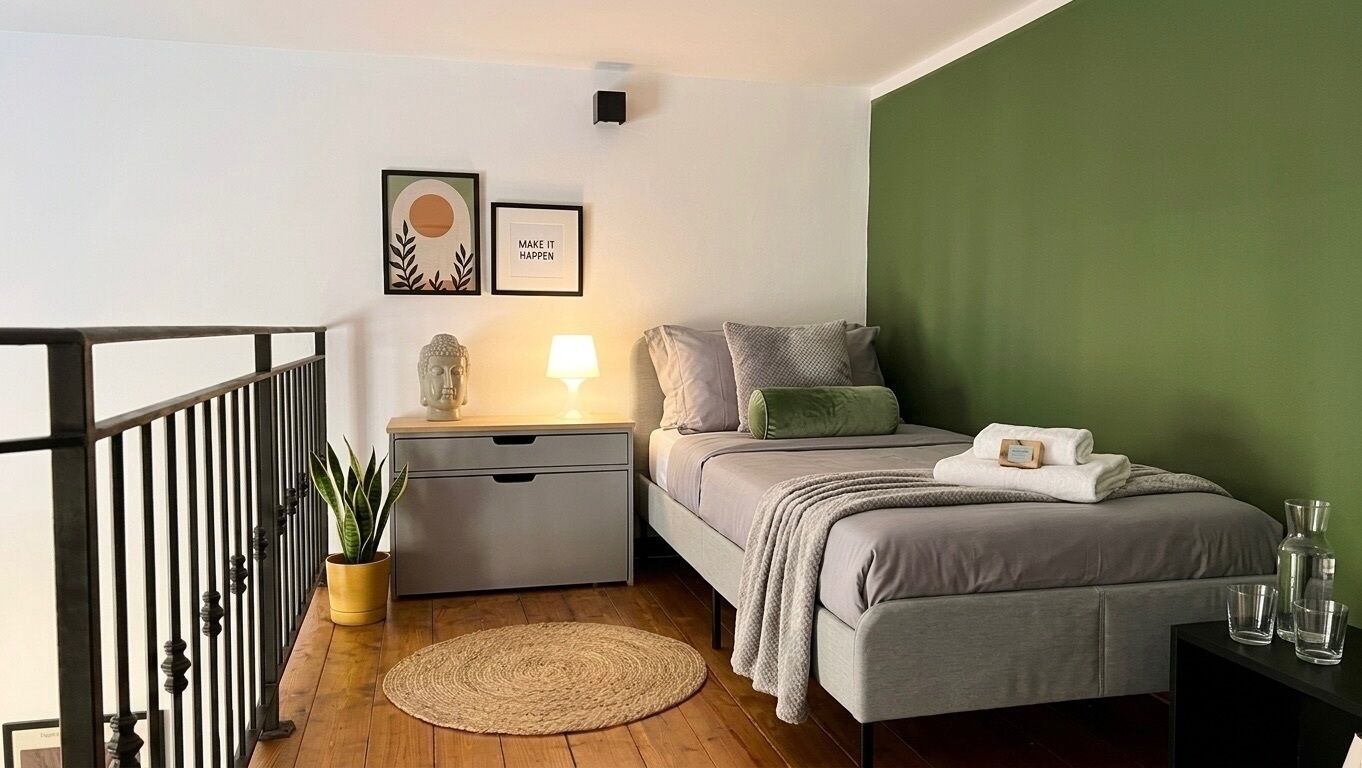 Ein Schlafzimmer mit Bett, Nachttisch, Lampe, Wandkunst und einer Wand in Grüntönen.