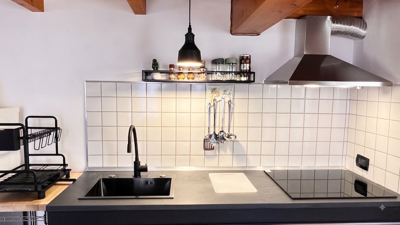 A modern kitchen with a black sink, stainless steel faucet, and a range hood above a tiled backsplash.