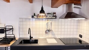 Una cucina moderna con lavello nero, rubinetto in acciaio inossidabile e cappa aspirante sopra un rivestimento a mosaico.