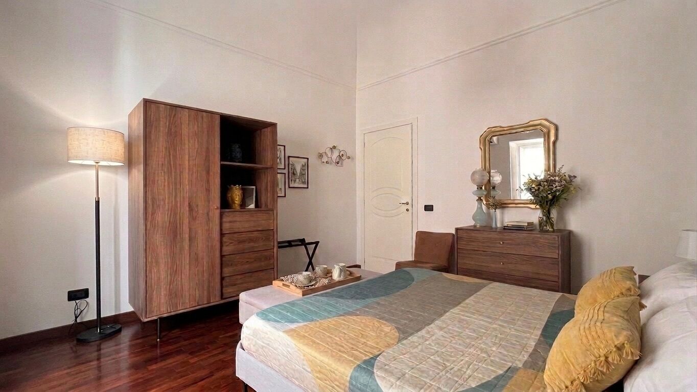 Ein Schlafzimmer mit Bett, Kleiderschrank, Nachttisch, Lampe und Spiegel.