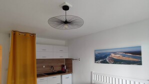 Un dormitori amb llit, finestra amb vistes, zona de cuina i ventilador de sostre.