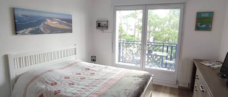 Un dormitorio con cama, escritorio, ventana y balcón.