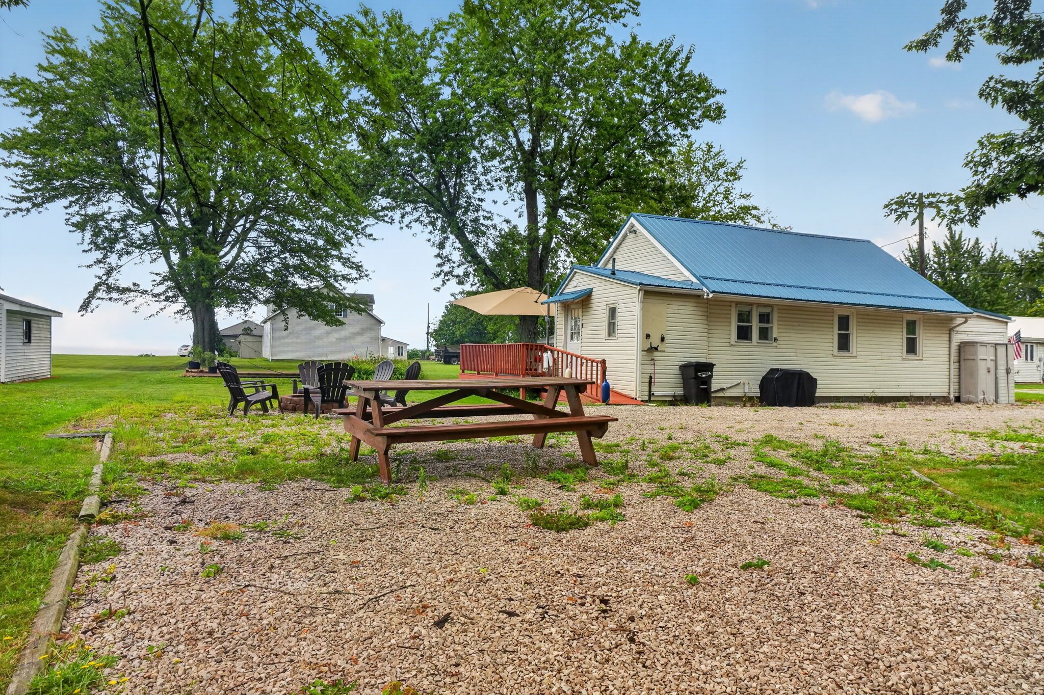 A rustic cabin with a gravel driveway, a picnic table, and outdoor seating.