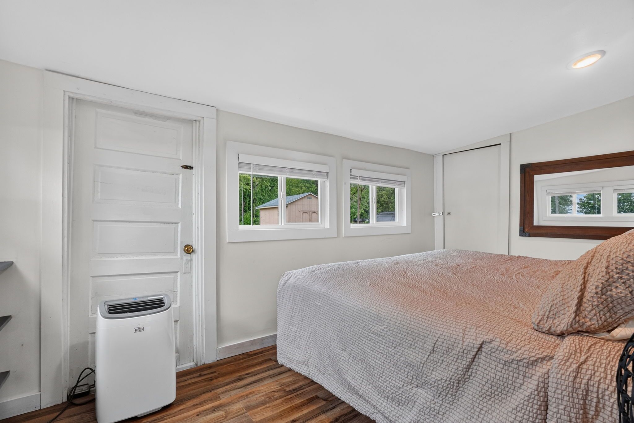 Quarto com cama, aquecedor, duas janelas e porta.