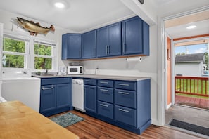 A compact kitchen with blue cabinets, a microwave, and a dishwasher.