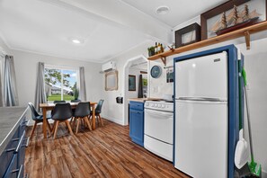 Een functionele keuken met een eethoek, met daarin een kookplaat, koelkast en een eettafel met stoelen.