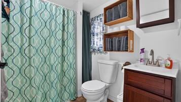 Un baño con inodoro, lavamanos con espejo y cortina de ducha.