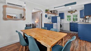 Une cuisine moderne avec des meubles de rangement bleus, une table à manger en bois et des chaises de couleur turquoise.