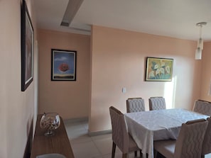 A dining area with a table and chairs, framed artwork on the walls, and a light fixture. - Apartment with full air conditioning near Mangueirão (Belém)