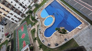 An aerial view of a residential area with a swimming pool, a basketball court, and a parking lot. - Apartment with full air conditioning near Mangueirão (Belém)
