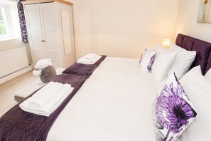 A hotel room with a bed, pillows, a bedside lamp, a wardrobe, and a window with curtains. - Thwaite Hill Barn, Thornthwaite -  with garden, parking and wood burning stove (Thornthwaite)