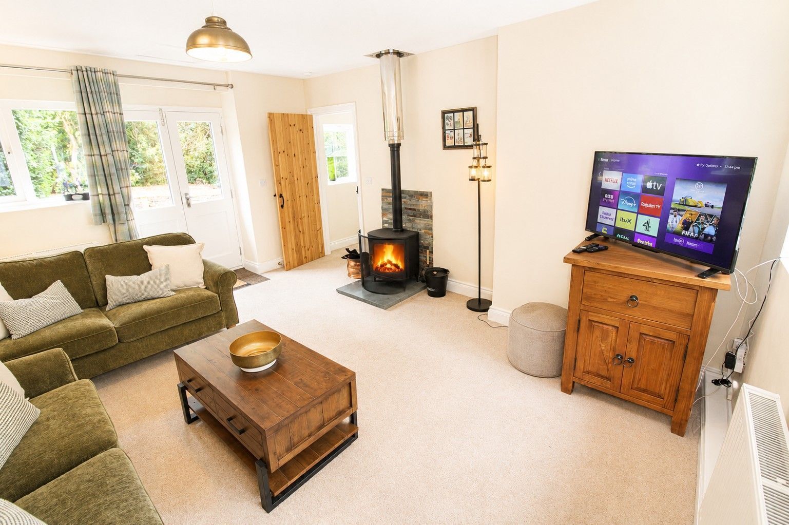 A living room with a sofa, a coffee table, a fireplace, a television, and a wooden cabinet.