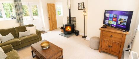 A living room with a sofa, a coffee table, a fireplace, a television, and a wooden cabinet.