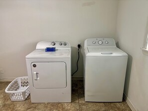 A laundry area with two white washing machines and a white laundry basket.