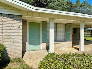 A residential building with a brick facade, a green door, and a covered porch with shutters. - Spacious 3 bedroom house in pleasant Monroe with AC (Monroe)