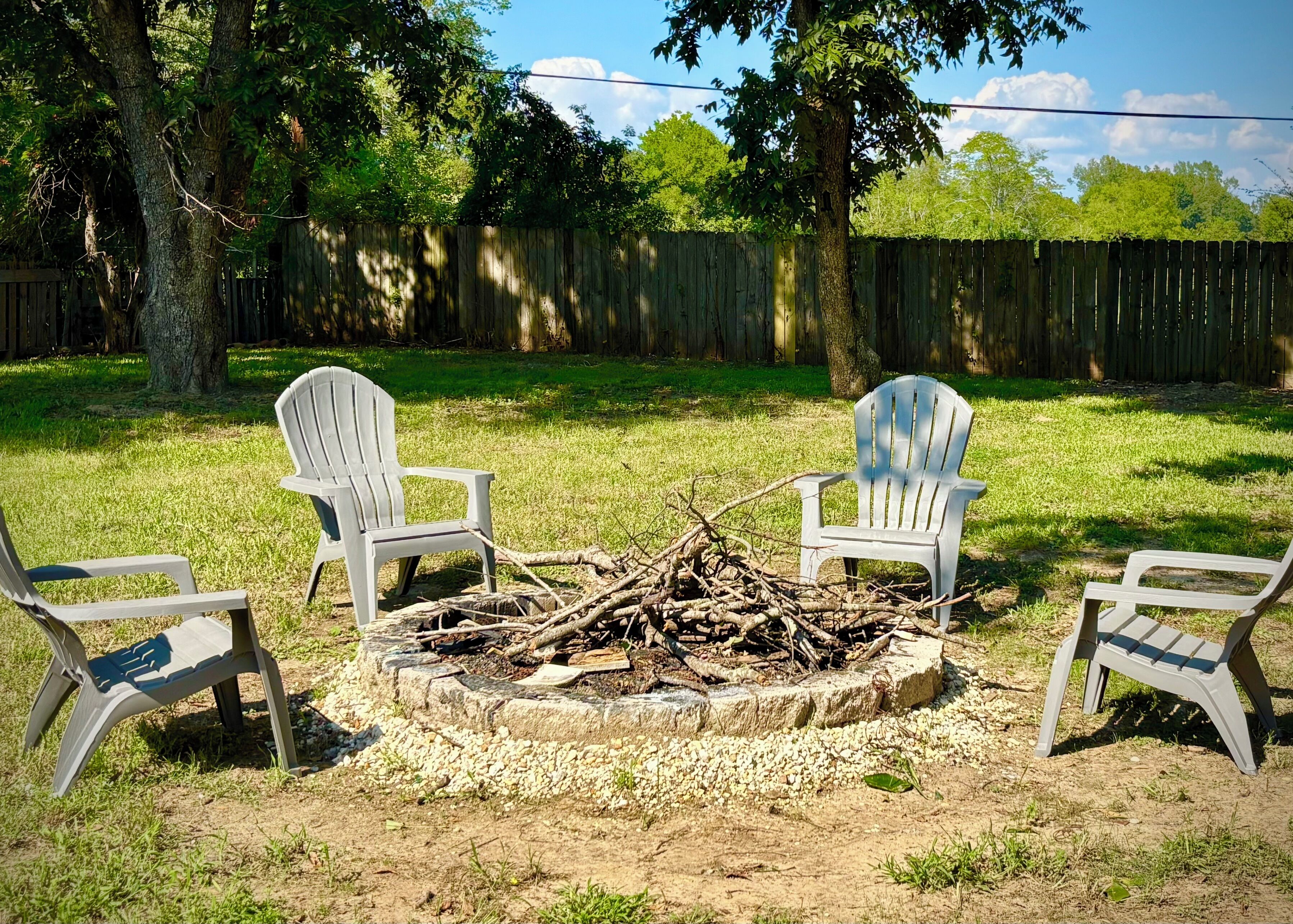 Un jardin avec un foyer entouré de fauteuils Adirondack.