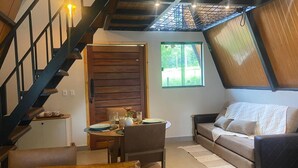 Una sala de estar moderna con una escalera de madera, un comedor con una mesa y sillas, y un sofá.