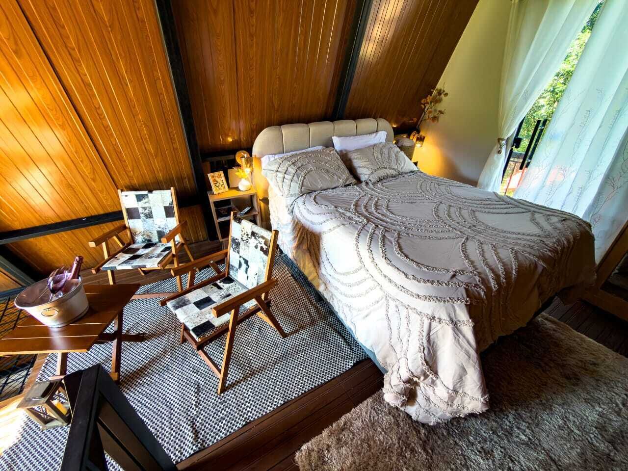 A bedroom with a large bed, wooden furniture, and a view of the outdoors.
