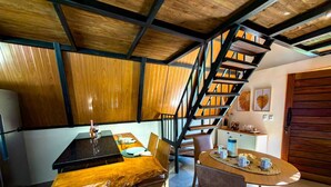Una cocina con una mesa de comedor, sillas, una escalera y una pequeña isla con cafetera.