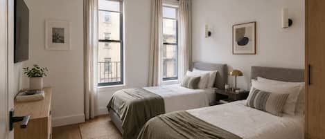 Un dormitorio con dos camas, un televisor, una mesita de noche con lámpara y una ventana con cortinas.