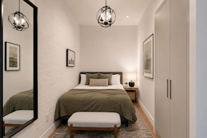 A bedroom with a bed, bedside table, lamp, and wardrobe. - Sprawling Townhome in the Heart of NYC (New York)