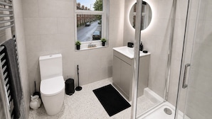 Un baño moderno con inodoro, lavamanos y ducha.