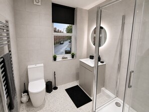 A modern bathroom with a toilet, sink, and shower. - Cosy Modern 2BR Leeds City Stay | Free Parking 1000mbps Wi-Fi (Leeds)