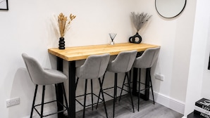 Un comedor con una mesa de madera, cuatro sillas grises y un espejo redondo en la pared.