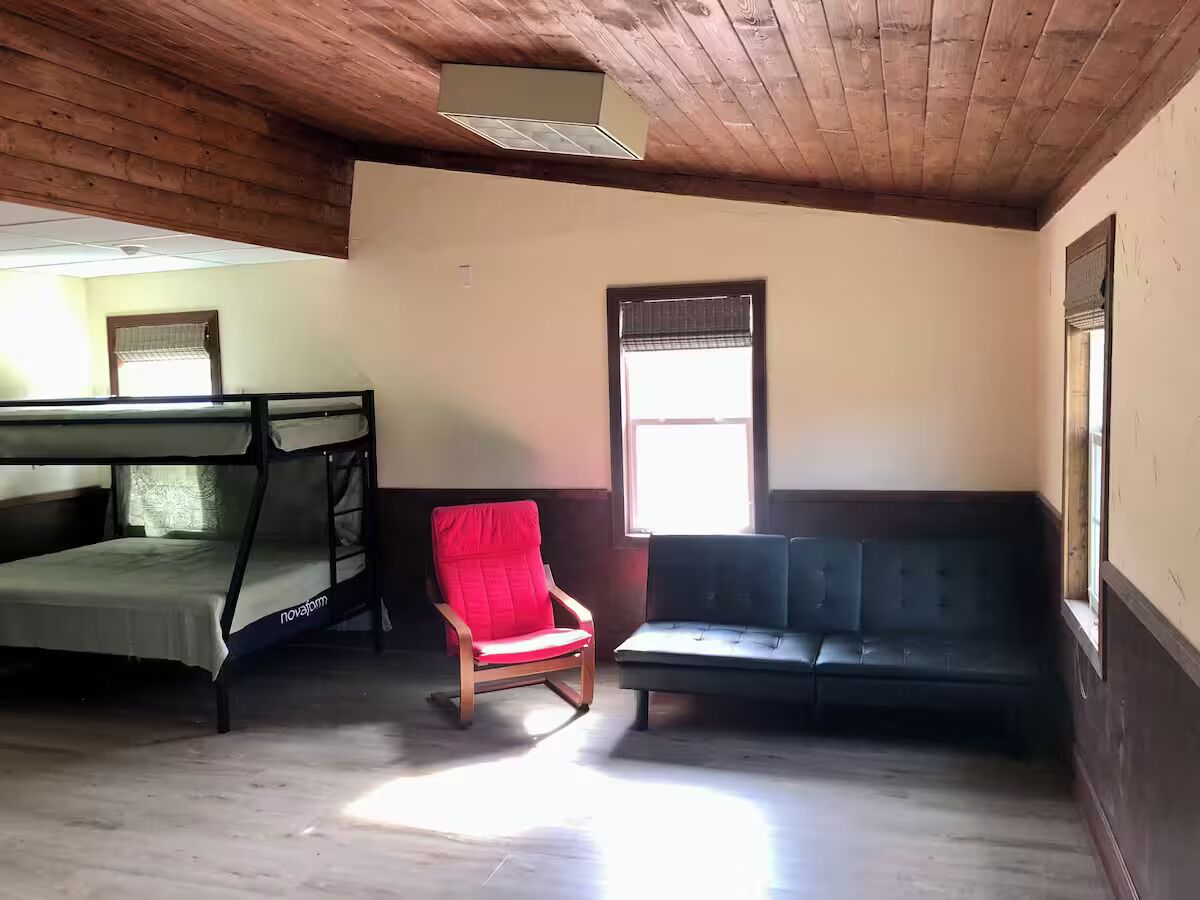 Quarto com beliche, uma cadeira vermelha e um sofá.