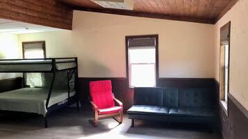 Quarto com beliche, uma cadeira vermelha e um sofá.