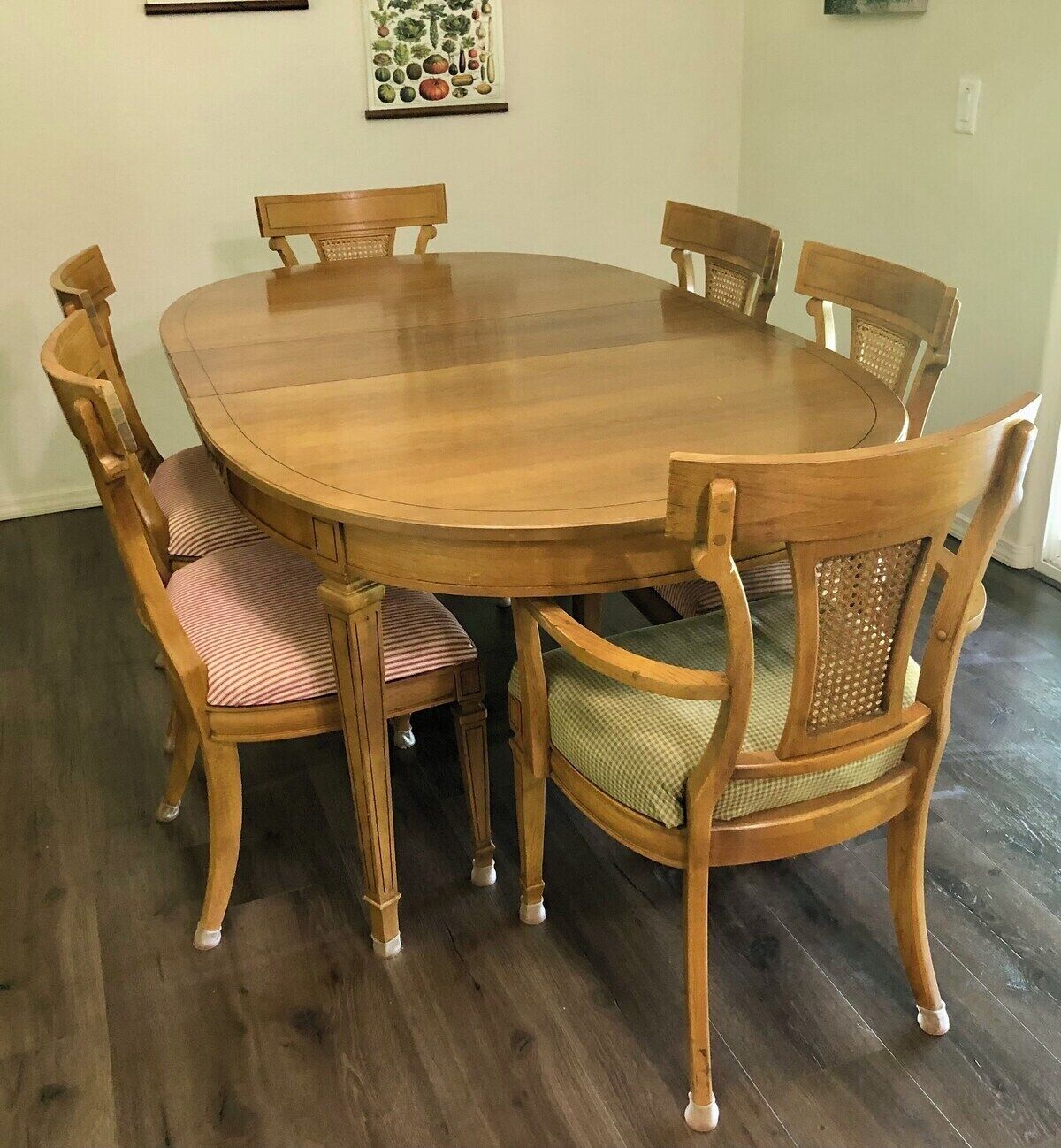 A round wooden dining table with six chairs, each with a cushioned seat.