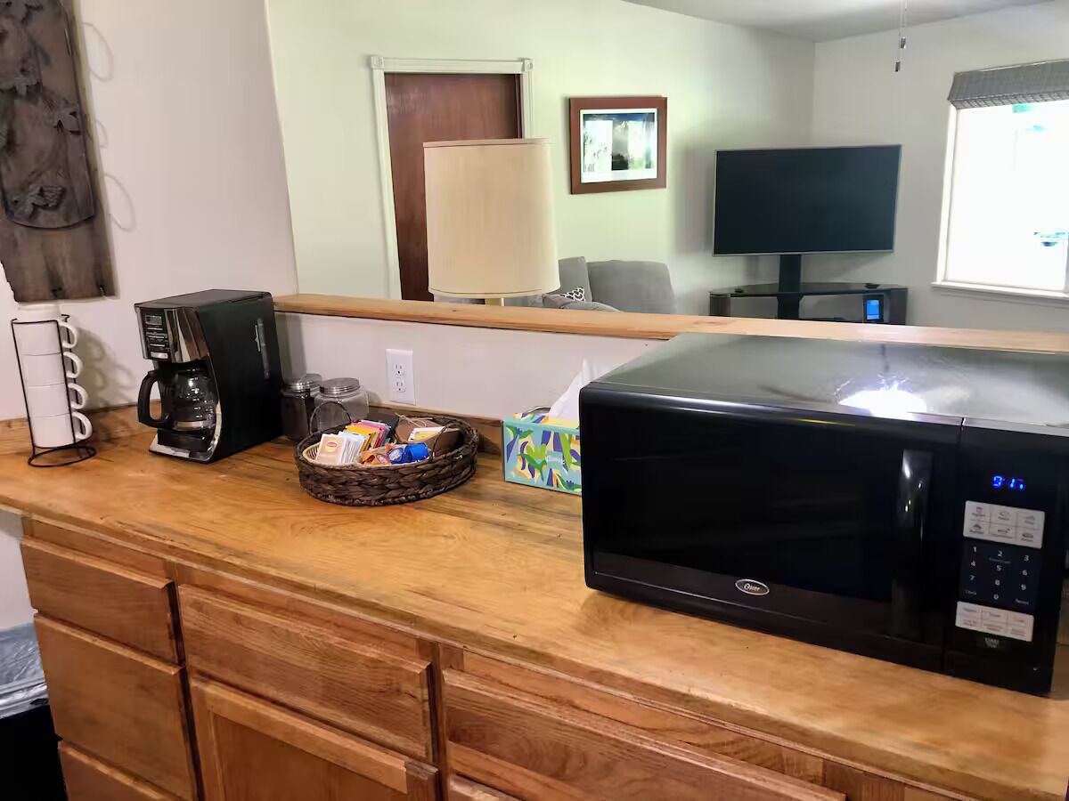 A kitchen with a microwave, coffee maker, and a basket of items on the counter.