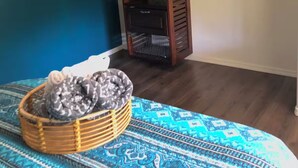Una habitación con una cama, un armario de madera y una cesta en el suelo.