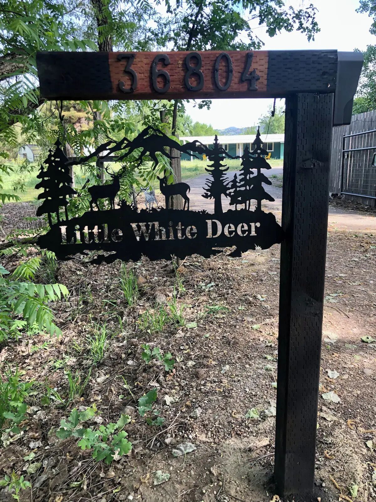 Et træskilt med nummeret '56804' og teksten 'Little White Deer', der viser en silhuet af et hjort og træer.