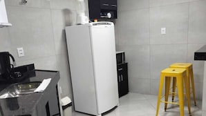 Una cocina moderna con estufa, refrigerador y un taburete amarillo.