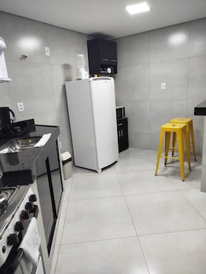 Eine moderne Küche mit Herd, Kühlschrank und einem gelben Hocker.