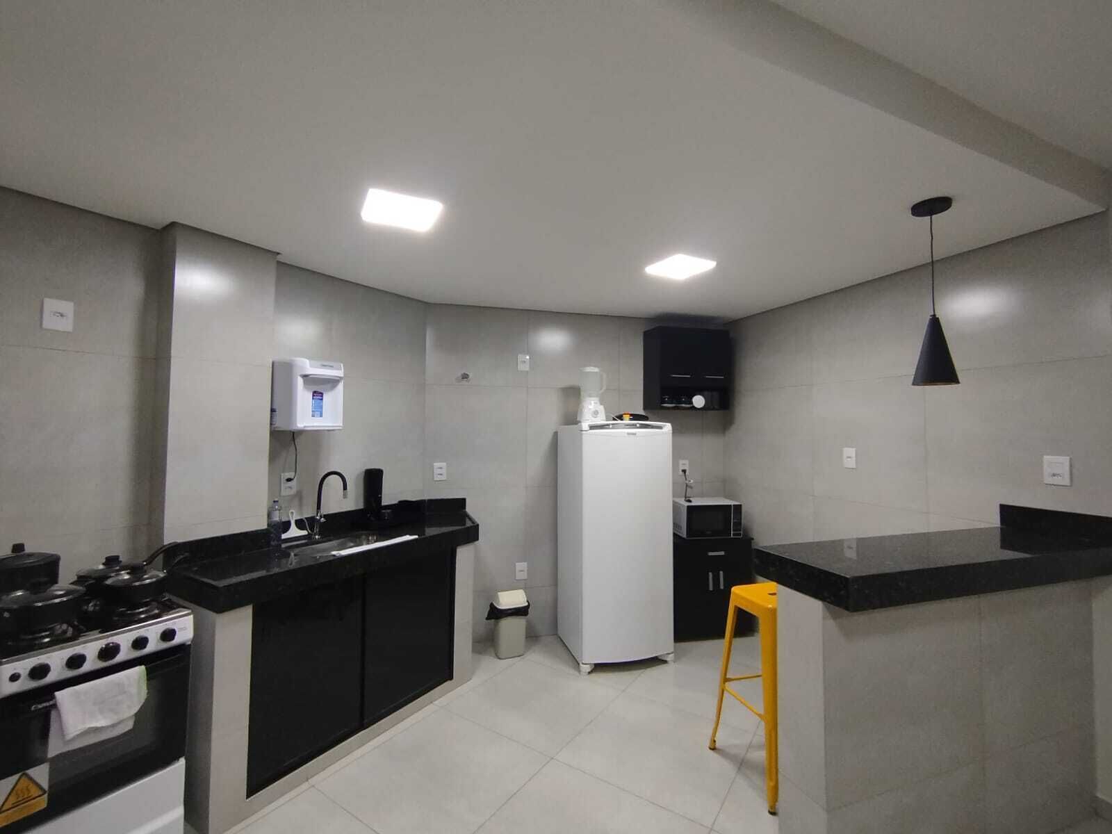 A modern kitchen with a stove, sink, refrigerator, and a bar counter.