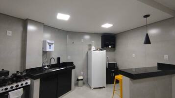 A modern kitchen with a stove, sink, refrigerator, and a bar counter.