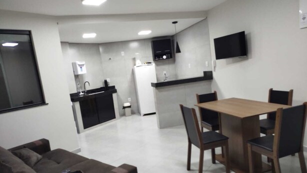 A modern kitchen with a dining area, a sofa, and a TV mounted on the wall. - Central apartment, 1st floor, with air conditioning, garage, smart TV. (Montes Claros)