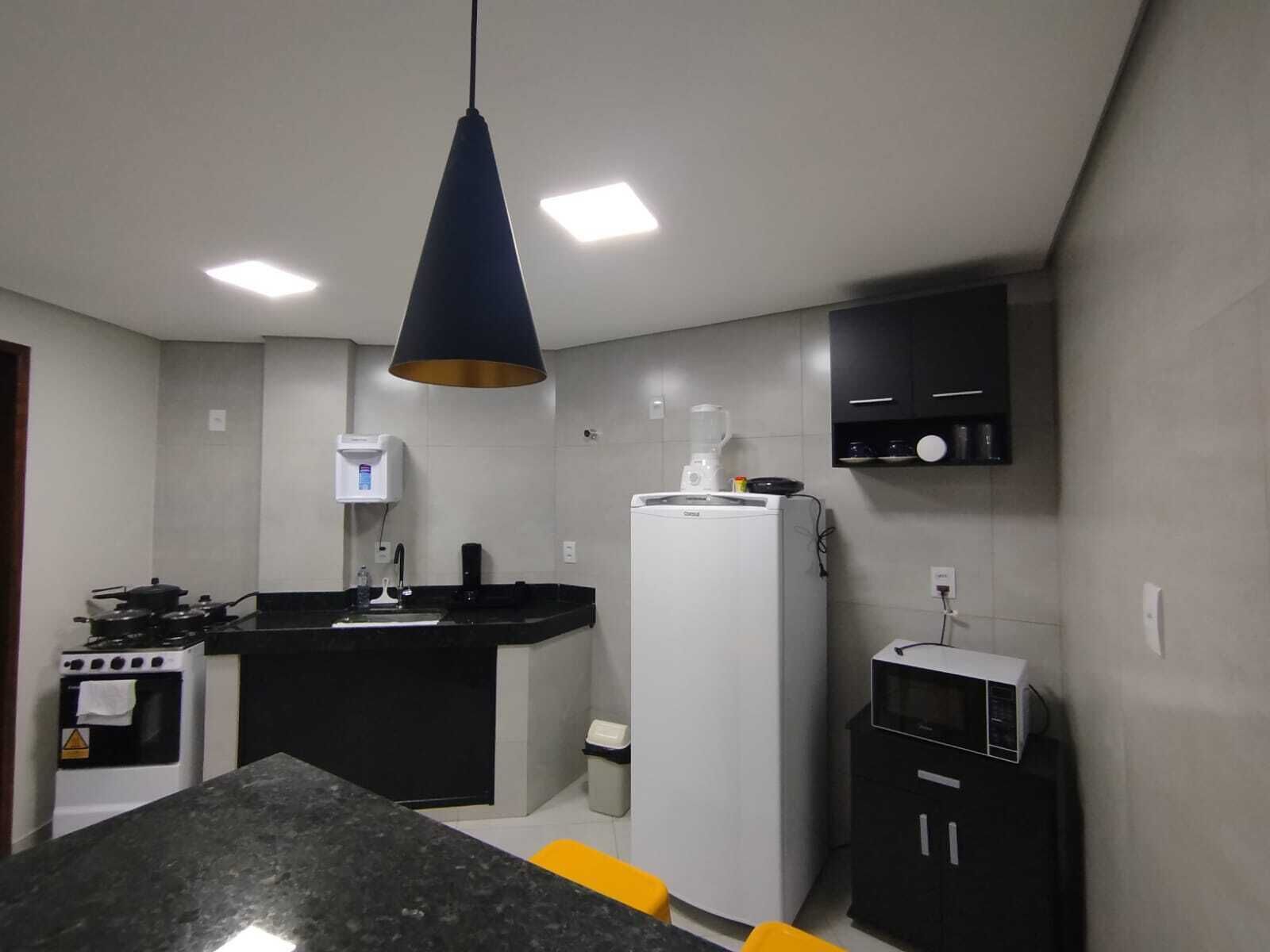 Una cocina compacta con una isla central, estufa, refrigerador y microondas.