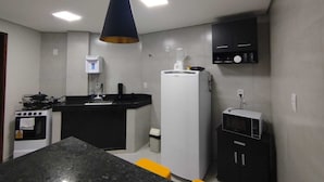 Una cocina compacta con una isla central, estufa, refrigerador y microondas.